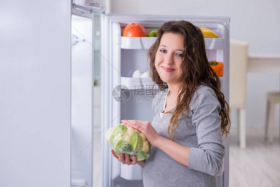 孕妇在冰箱附近寻找食物和零食图片