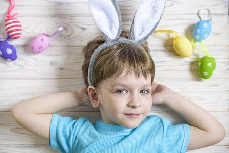 复活节概念快乐的可爱孩子穿兔子耳朵躺在木头背景图片