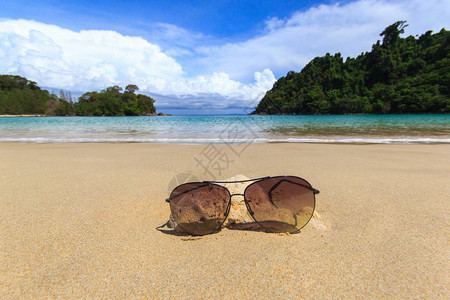 在沙滩上贴深墨镜夏季蓝天背景的图片