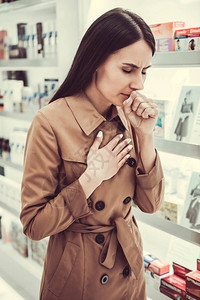 美丽的年轻女子在药店找药时咳图片