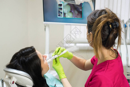 牙医在牙科诊所用远程摄像头检查女人的牙齿图片