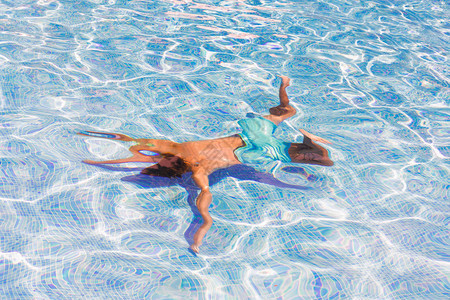 男孩在蓝色瓷砖池水下游泳图片