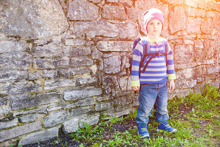 一个小男孩背着包站在石墙附近孩子在图片