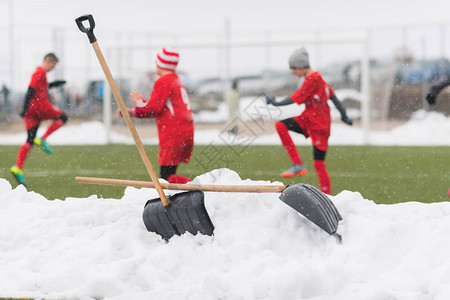 从足球场打扫雪后在积雪堆中刮雪落雪时孩子图片