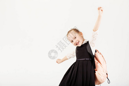 有趣的微笑小女孩背着大背包跳跃和在白色背景下玩乐看着相机学校理图片
