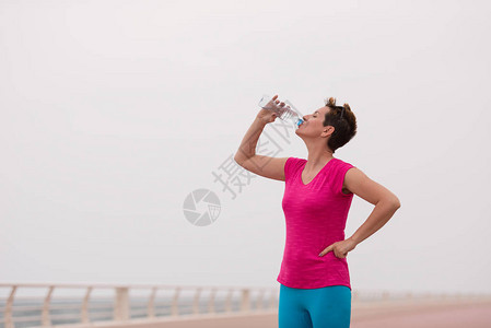 健身女人在海边长廊跑步后喝水图片