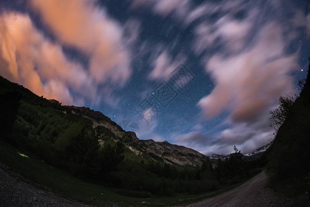 与运动模糊彩云和明亮的月光欧洲阿尔卑斯山广阔的夜景图片