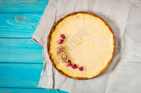 自制芝士蛋糕健康有机夏季甜点馅饼芝士蛋糕蓝色木桌上的芝士蛋糕干花的图片