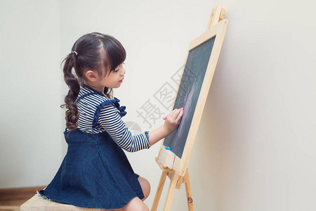 亚洲女孩在教室儿童学生和学校内用古老背景的粉笔画花给图片