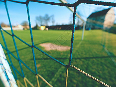 黄蓝横越足球网足球在目标网中野外操场上草地背景图片