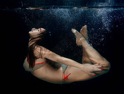 黑暗背景的年轻迷人美女自由潜水员的水下肖像画图片