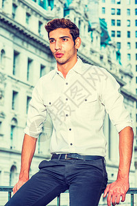 年轻的商人一位穿着白衬衫黑裤子的年轻大学生坐在商业区的前面图片