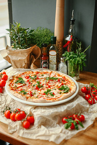 餐桌上供应培根奶酪和西红柿的披萨图片