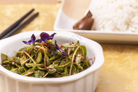 一张亚洲沙拉上满是红胡椒糊和一碗大米的近图片