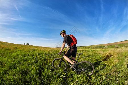年轻的骑自行车者骑山地自行车反对美丽的日落在农村图片