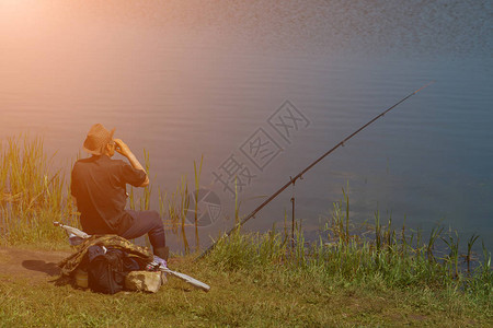 有钓鱼棒的渔夫在河边钓图片