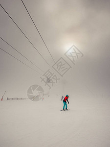 穿着荧光工作服的滑雪板女子和一些在浓雾中的滑雪者图片