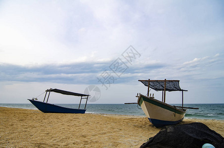 传统渔船在多云天空的沙滩上图片
