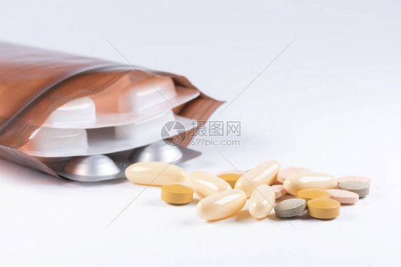 白色背景上带塑料袋的片剂和胶囊中的药物图片