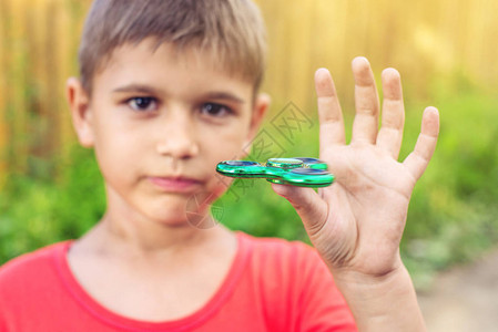 一个男孩玩扭在他的手在户外的微调框儿童抗应激玩具的趋势图片
