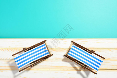 木质表面和蓝色背景上的两把条纹沙滩椅图片