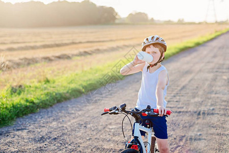 戴自行车头盔的男孩喝瓶装水骑自行车的孩子图片