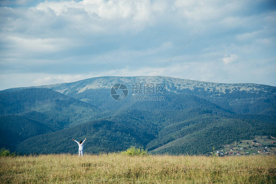 夏日里远距离描绘山峦背景的田野中的女人图片