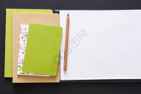 具有一套彩色笔记本素描手册和黑背景铅笔以及复制空间平铺开办概念和文具用品的模背景图片