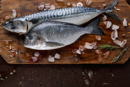 海鲜餐厅背景新鲜鲭鱼和多拉鱼在棕色桌子上的木板上健康食品的有机烹饪原料顶视背景图片