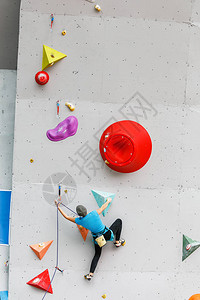 体育运动员或业余爱好者开始爬上大型人造墙壁在现代多彩的室背景图片