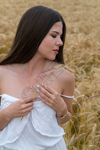 身穿白色夏季西装的女孩站在小麦田里图片