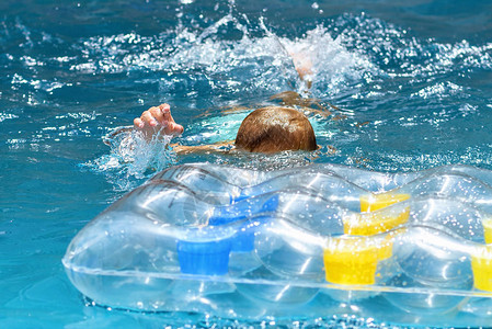 白种人红发男孩在蓝色水池里游泳图片