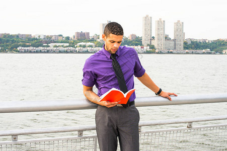 一个穿着紫色衬衫灰色裤子和黑色领带的年轻英俊的大学生图片