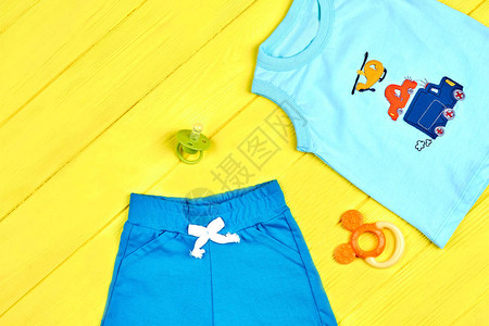 男婴新夏装婴儿男孩T恤纺织短裤奶嘴黄色夏季背景的牙胶婴图片