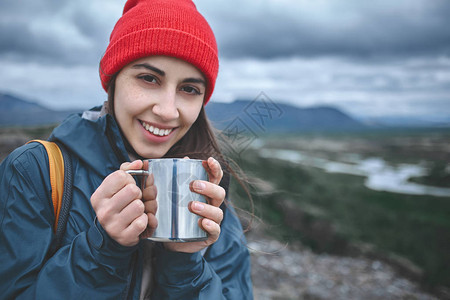 身着温暖衣服和红帽子的女孩拿着铁杯图片