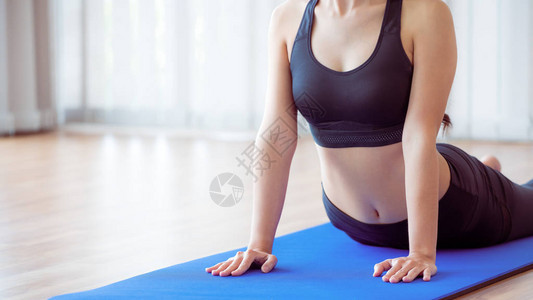 在瑜伽垫上的室内健身房锻炼的年轻女人图片