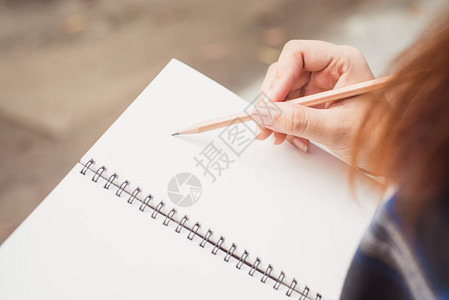 写在螺旋记事本放在木制桌面上与各项目中的女人的手的特写老式的影响风格图片图片