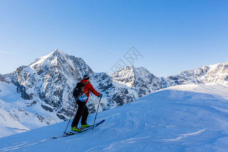 登山者偏远地区滑雪沿着雪脊行走图片