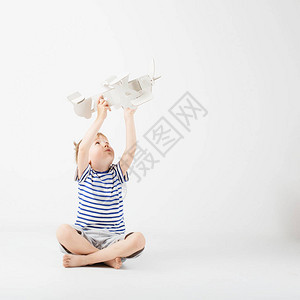 儿童男孩玩纸玩具飞机坐在地板上图片
