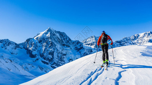 登山者偏远地区滑雪沿着雪脊行走图片