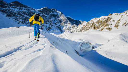 登山者偏远地区滑雪沿着雪脊行走图片
