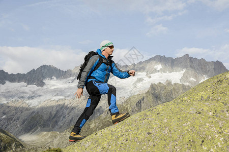 一位运动型登山者在瑞士阿尔卑斯山攀登山顶图片