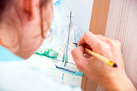 特写女艺术家用细木刷和水彩在海中画一艘游艇图片