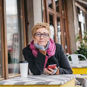 女郎坐在咖啡馆外喝着咖啡用智能图片