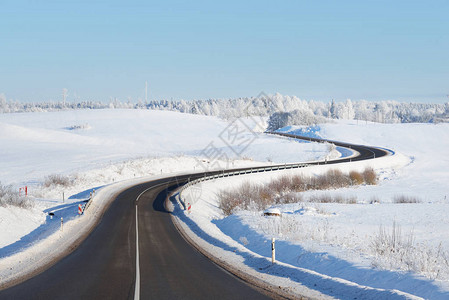 雾凇下山森林高速公路在阳光明媚的冬季背景