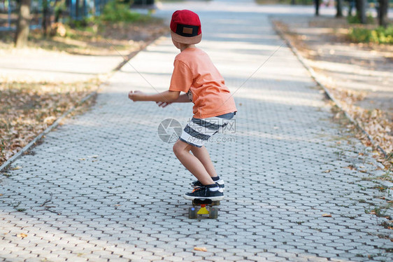带着便士滑板的城市小男孩子们在夏季公园滑冰城市风格城市孩子孩子图片