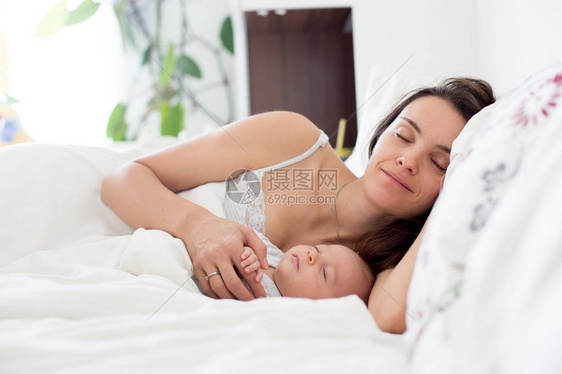 年轻母亲与婴儿同床共枕抱着他怀着她的双图片
