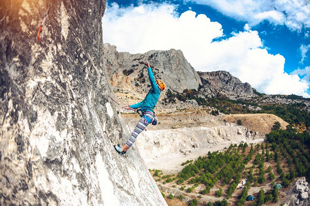 岩石上的攀岩者女孩在美丽的山景和云彩的背景下爬上岩石积极的生活方式自然运动克服困图片