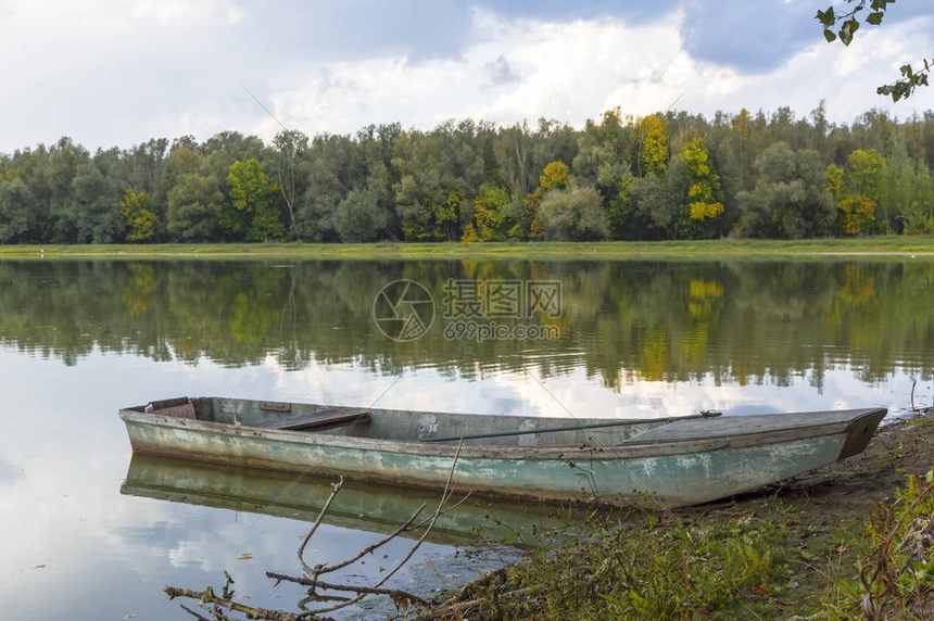 秋天湖边沙滩上被淹的旧木船图片