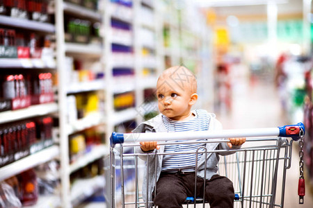 超市的小可爱宝坐在购物车里的婴图片